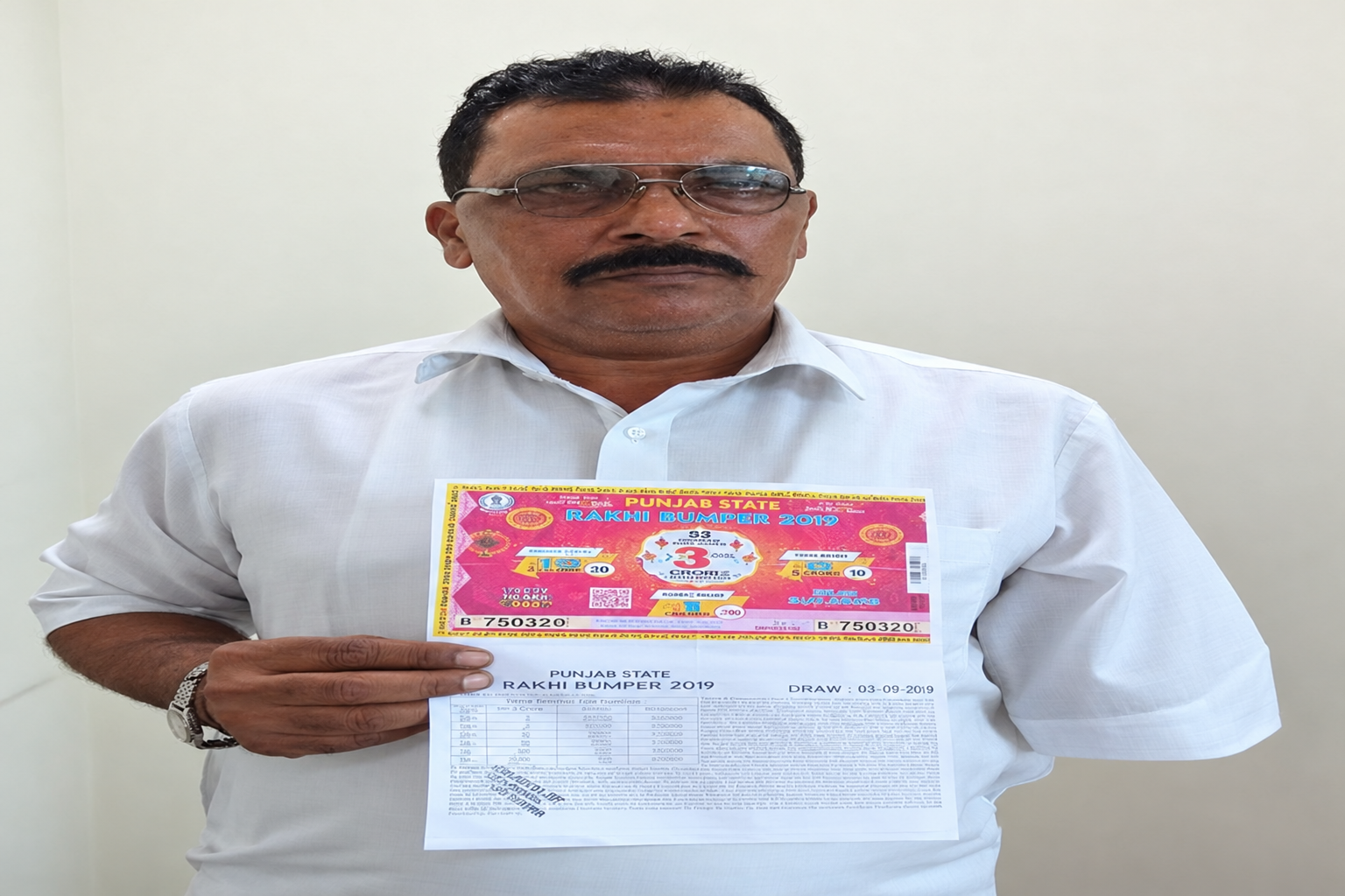 Person holding a Punjab State Rakhi Bumper ticket and printed sheet